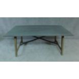 A farmhouse style dining table with zinc top on limed trestle style supports united by metal