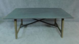 A farmhouse style dining table with zinc top on limed trestle style supports united by metal