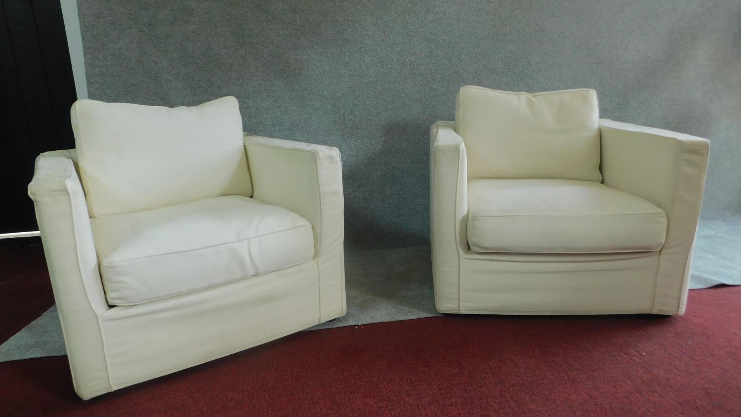 A pair of armchairs upholstered in cream, makers label to base. H.79cm