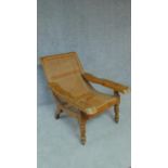 A colonial teak framed reclining planter's chair with foldout foot rests on turned tapering