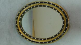 A 19th century oval wall mirror with gilt and ebonised framed and beaded decoration. 72x57cm