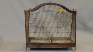 A Victorian style wooden bird cage with exotic birds on perches with wire bars and metal carrying