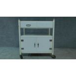A white painted and metal medical cabinet/trolley with drawers and cupboards on casters. H.90 W.86