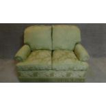A two seater sofa in floral green upholstery. 97x145x80cm