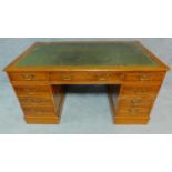 A Georgian style three section yew pedestal desk with green tooled leather inset top and an