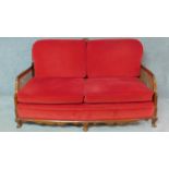 A mid 20th century walnut framed bergere sofa with caned panelled back and sides in red upholstery