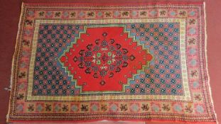 A Persian rug with central pendant medallion on a red field surrounded by repeating petal motives