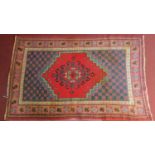 A Persian rug with central pendant medallion on a red field surrounded by repeating petal motives