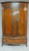 An early 20th century Georgian style mahogany bowfronted wardrobe fitted base drawer on swept