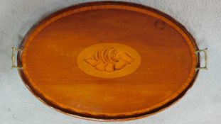 An Edwardian mahogany oval tray with satinwood conch shell inlay and crossbanding with twin brass