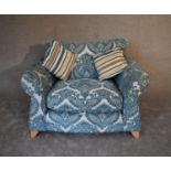 A large pale blue upholstered armchair with scroll arms and splay block feet. H.76 x 120cm