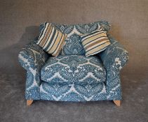 A large pale blue upholstered armchair with scroll arms and splay block feet. H.76 x 120cm