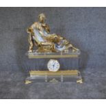 A large French Empire style mantel clock with gilt metal reclining figure above perspex case on gilt
