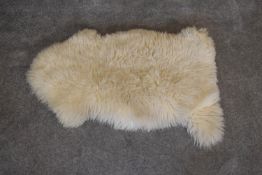 A natural sheepskin rug. L.100 x 59cm