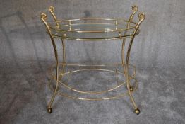 A brass framed oval glass topped drinks trolley on casters. 85cm wide x 85cm high.