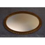 A gilt framed oval wall mirror with gadrooned and floral edging. L.115cm x 75cm.