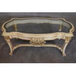 A cream and gilt Empire style coffee table with allover carved decoration fitted shaped bevelled