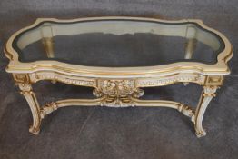 A cream and gilt Empire style coffee table with allover carved decoration fitted shaped bevelled