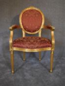 A Louis XVl style gold framed open armchair in rouge damask upholstery. H.104 x 62cm