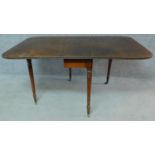 A Regency mahogany drop flap dining table on turned tapering supports terminating in brass cup