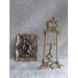 A copper relief moulded wall plaque with male and female figures and a vintage brass openwork easel.
