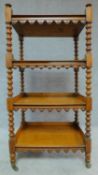 A Victorian honey oak four tier buffet on turned tapering supports terminating in brass cup casters.