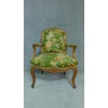 A carved beech framed French style fauteuil in green floral upholstery. H.96cm