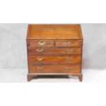 A Georgian oak bureau with fall front revealing fitted interior with mahogany and satinwood inlaid