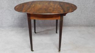 A Georgian mahogany circular drop flap table on square tapering fluted supports terminating in brass