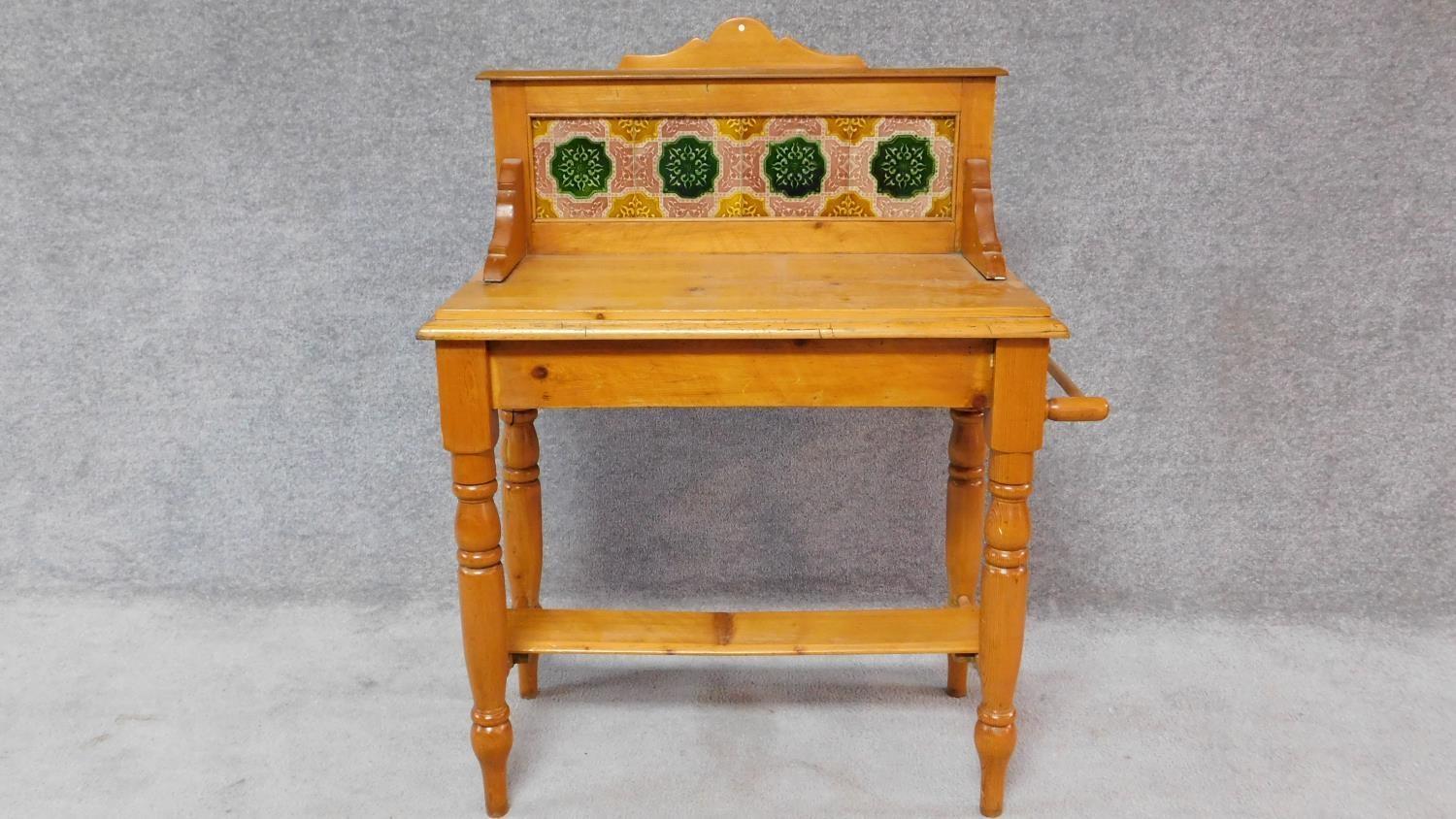 A Victorian pine washstand with original inset coloured tiles to the back fitted with a towel rail