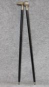 An ebonised walking stick with white metal handle and another similar. W.93cm