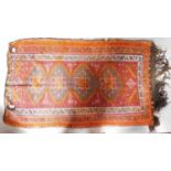 A hand woven kilim rug with four interlinking pendant medallions on a terracotta field surrounded by