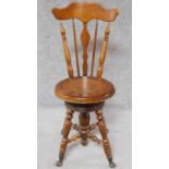 A Victorian walnut revolving piano stool with foliate carving to the back on reeded stretchered