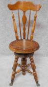 A Victorian walnut revolving piano stool with foliate carving to the back on reeded stretchered