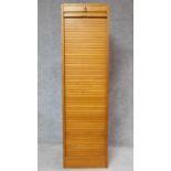 A mid 20th century light oak tall filing cabinet fitted tambour shutter and shelved interior. H.