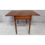 A 19th century mahogany drop flap Pembroke table on ring turned tapering supports terminating in