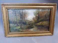 A gilt framed 19th century oil on canvas of a couple sitting under trees by a river. Indistinctly