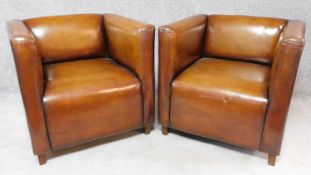 A pair of tan leather club armchairs on square supports. H.74 W.76 D.72cm