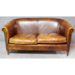 A tan leather upholstered twin seat tub sofa on tapering supports. H.78 W.147 D.82cm