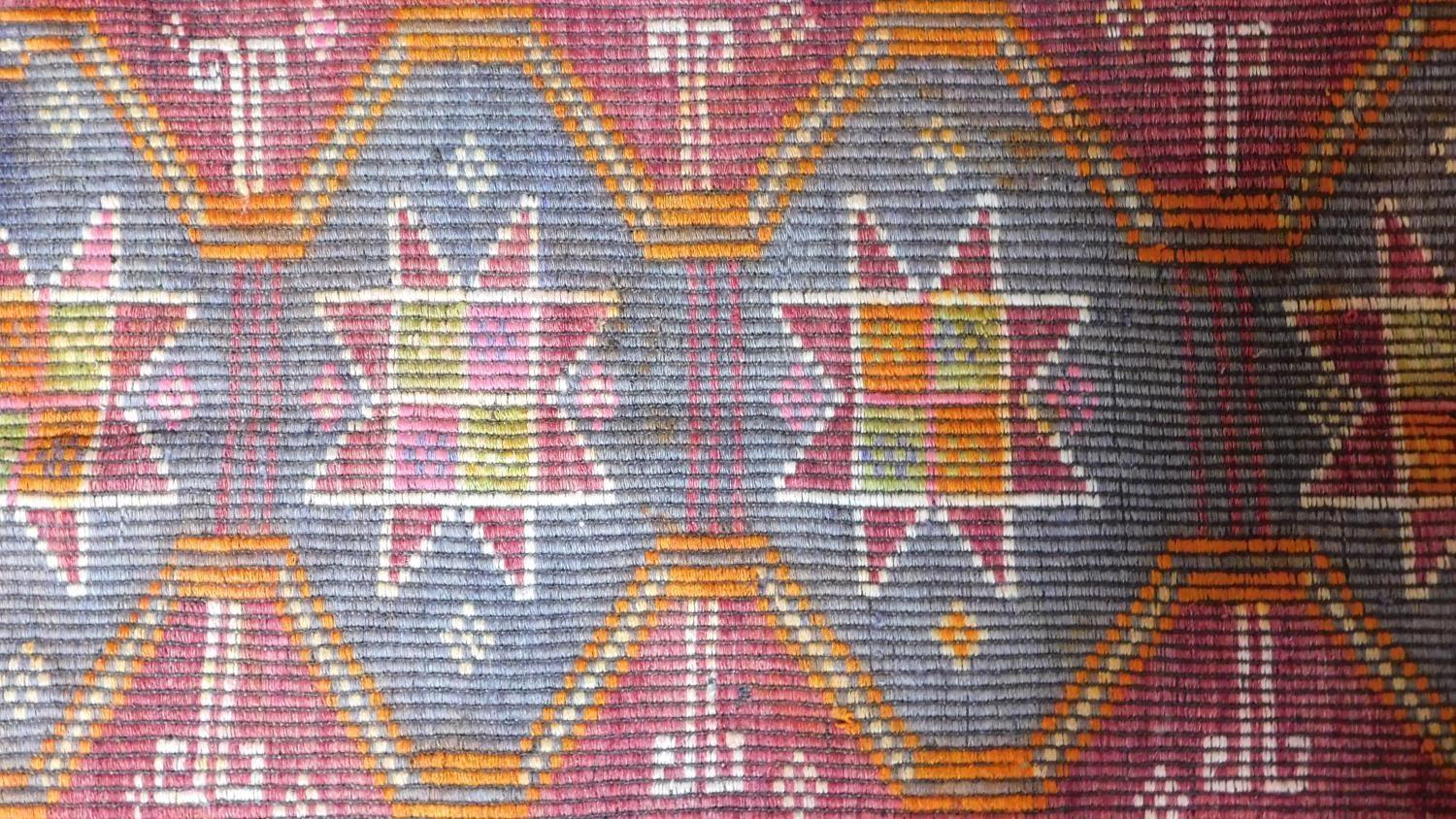 A hand woven kilim rug with four interlinking pendant medallions on a terracotta field surrounded by - Image 2 of 5