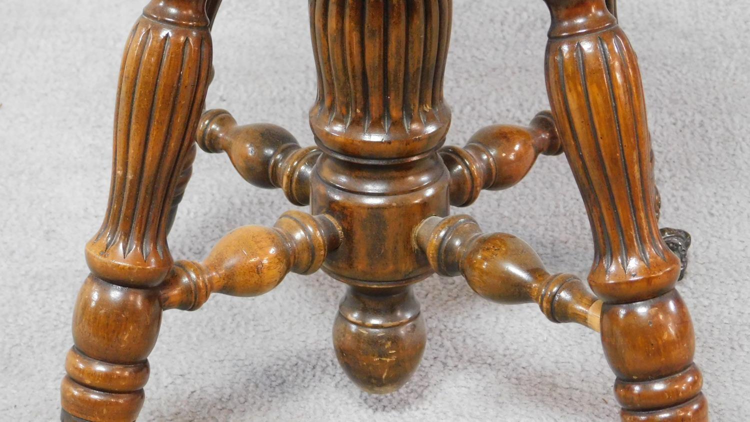 A Victorian walnut revolving piano stool with foliate carving to the back on reeded stretchered - Image 6 of 14