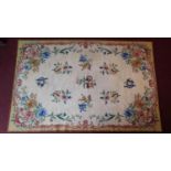 A tapestry style hand knotted carpet with allover floral design within Rococo scroll borders.