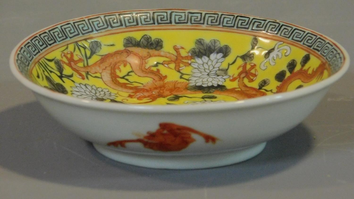 A Chinese yellow ground ceramic dish depicting two dragons, one red and one black. Greek key pattern - Image 2 of 6