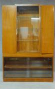A mid 20th century teak bookcase with glazed central section flanked by panel doors on base fitted