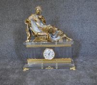 A large French Empire style mantel clock with gilt metal reclining figure above perspex case on gilt