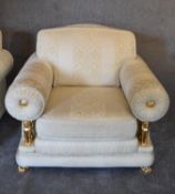 A pair of armchairs in cream fabric with gold detailing and inset gilt metal griffins supporting the