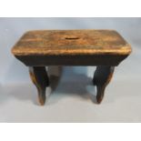 A 19th century stained pine milking stool. 58 cm L, 26cm D and 47 H.
