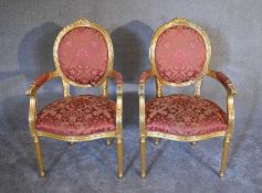 A pair of gilt framed Louis XVl style open armchairs in rouge damask upholstery - H.105 x 56cm