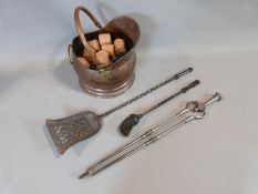 A trio of fire irons and a copper coal bucket filled with coal and fire logs. Fire irons include,