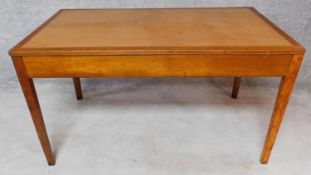 A mid 20th century oak writing table on square tapering supports. H.76 W.136 D.76cm
